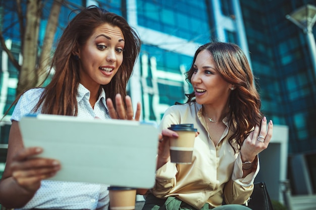 business women are sitting office park while using digital tablet holding disposable coffee cup business team is working online togetherness while consulting 360066 8461